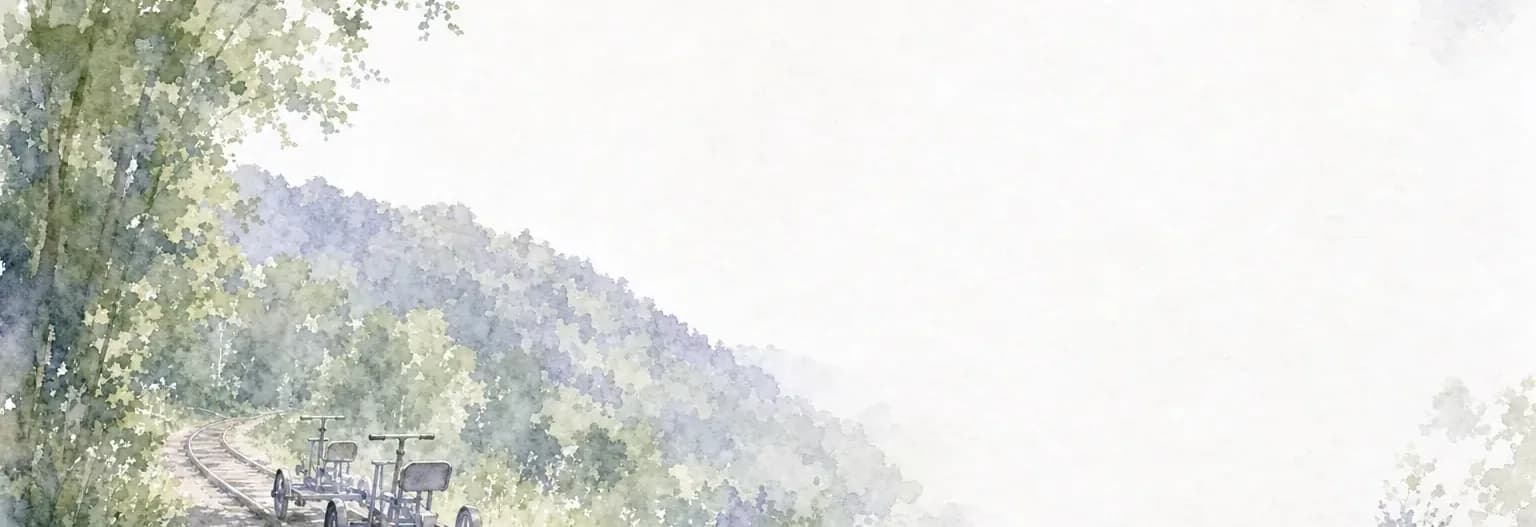 Watercolour of two pedal-powered rail bikes on a single railway track curving through a green wooded valley.