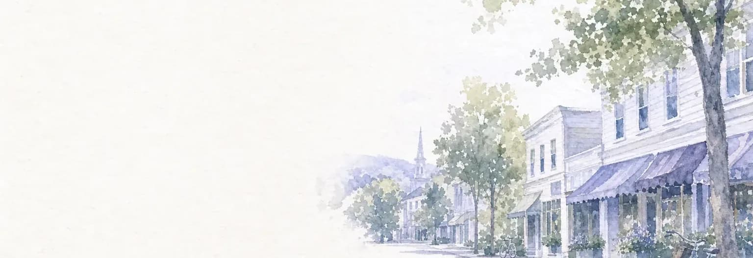 Watercolour of a village main street in summer, low clapboard storefronts under striped awnings and leafy trees, a bicycle at the kerb.